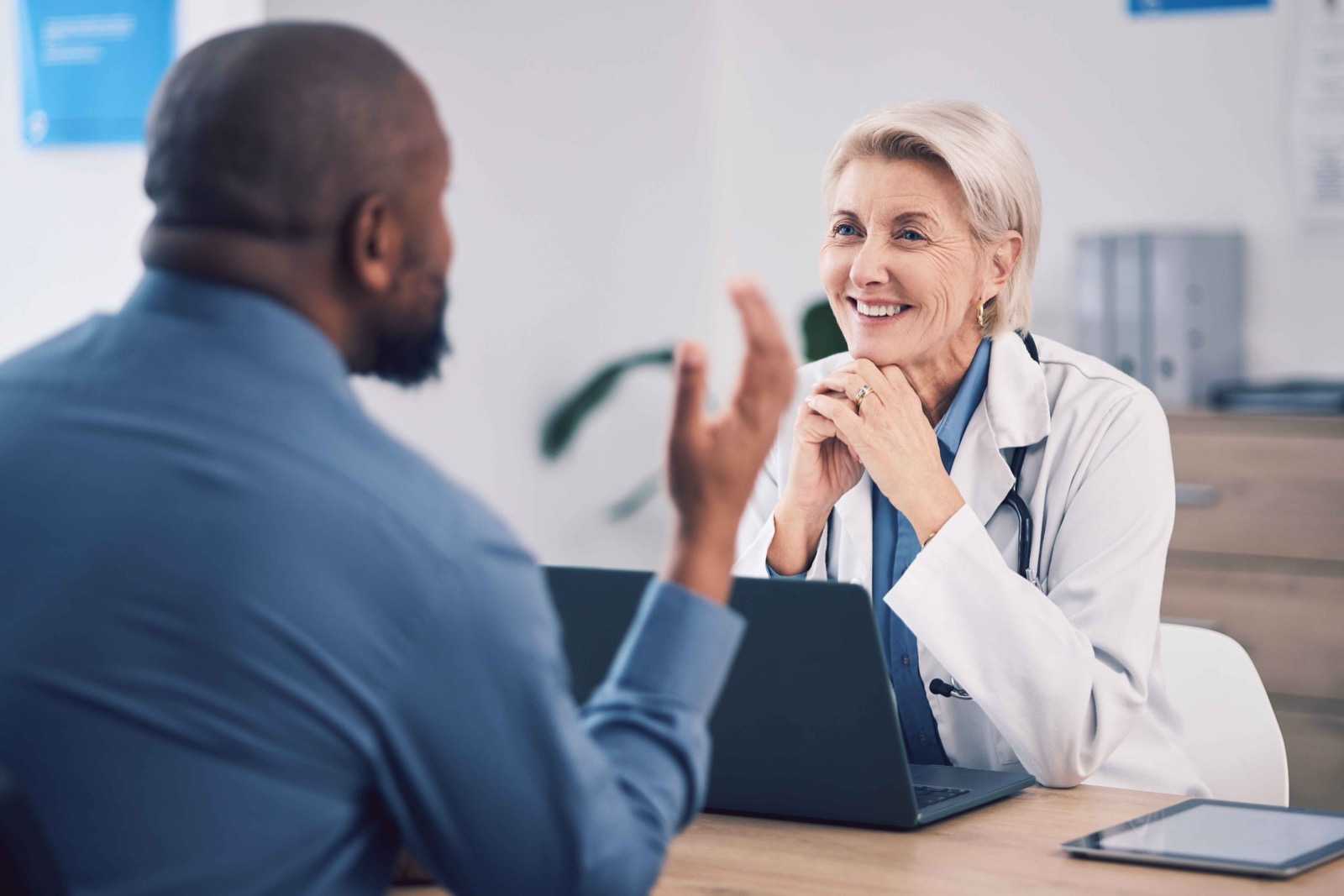 A smiling doctor speaking with a patient across a desk